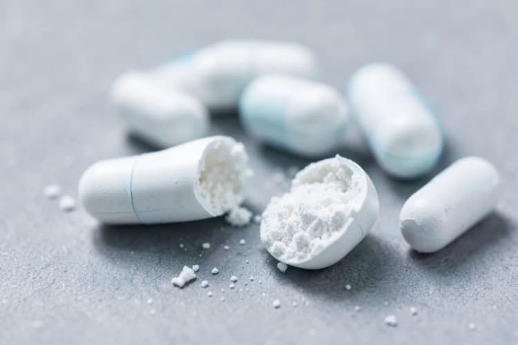 Cápsulas de antibiótico em close-up, com algumas espalhadas.